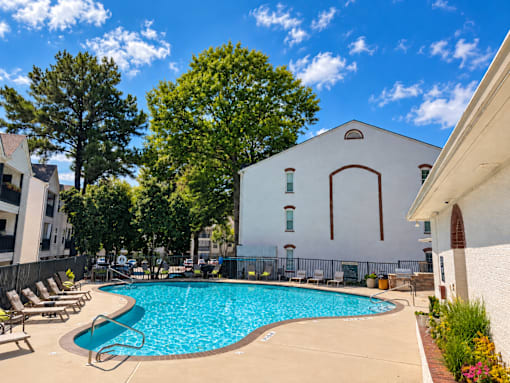 A pool surrounded by trees and a white building.