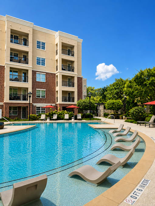 A large swimming pool with lounge chairs and a building in the background.