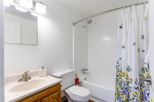 A white bathroom with a floral shower curtain.