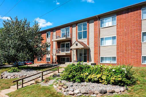 A red brick building with a landscaped front yard.
