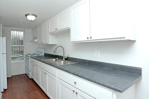 A kitchen with white cabinets and a grey countertop.