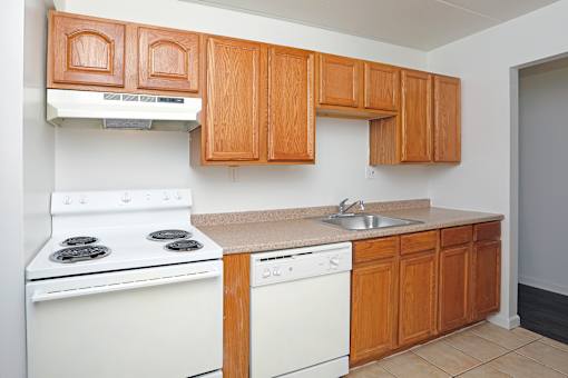 A kitchen with white appliances and wooden cabinets.