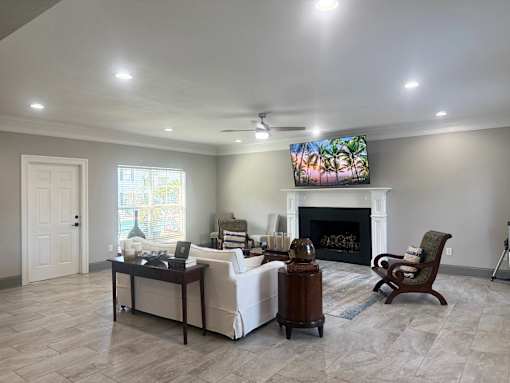 A living room with a fireplace and a television mounted above it.