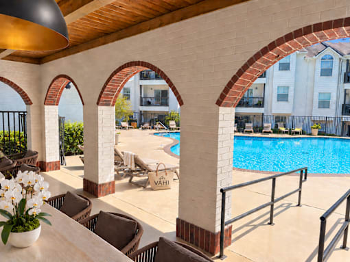 A pool area with chairs and a table with flowers.