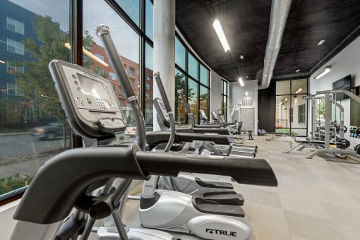 a gym with weights and exercise equipment in a building with large windows