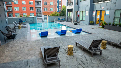 a pool of water in a courtyard with benches and chairs