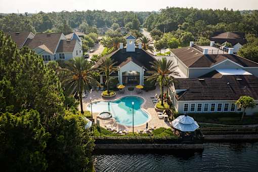 a aerial view of a swimming pool in front of a house and a lake