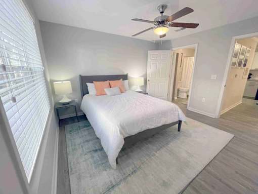 A bedroom with a bed, nightstand, and a ceiling fan.