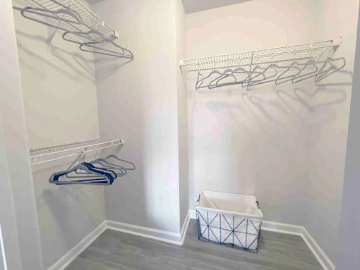 A white closet with clothes hangers and a basket.