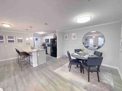 A dining room with a table set for two and a kitchen area in the background.