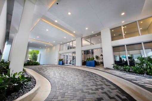 an office lobby with windows and a walkway with plants at Saba Pompano Beach, Pompano Beach, 33062