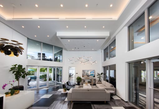 a living room with large windows and a couch and a table at Saba Pompano Beach, Pompano Beach, 33062