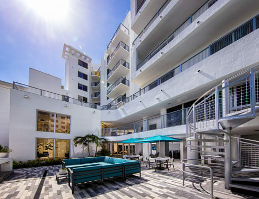 a large white building with a pool and umbrellas at Saba Pompano Beach, Pompano Beach, 33062