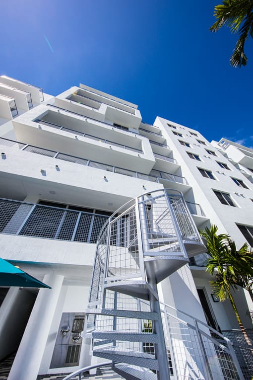 a white apartment building with a spiral staircase in front of a blue sky at Saba Pompano Beach, Pompano Beach, 33062