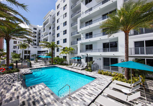 a swimming pool in front of a building with palm trees at Saba Pompano Beach, Pompano Beach, 33062