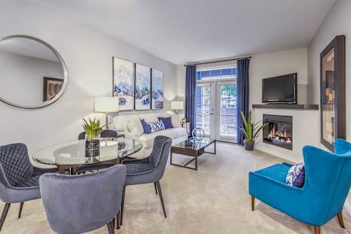 A living room with a fireplace, a blue chair, and a glass table.