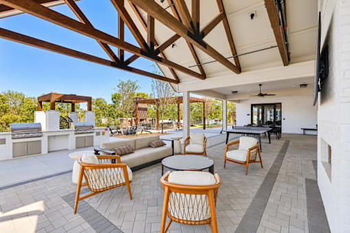 A patio with a white couch and wooden chairs.