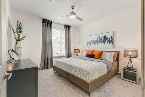 A bedroom with a bed, nightstand, and a painting on the wall.