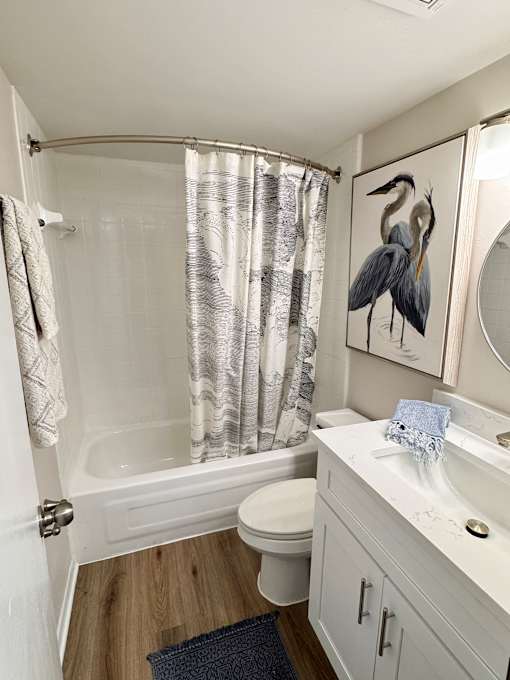 A bathroom with a white sink, toilet, and a shower with a curtain.