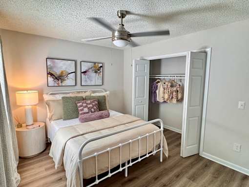 A bedroom with a bed, nightstand, and a ceiling fan.