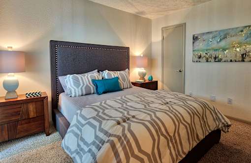 A bedroom with a large bed and a painting on the wall.