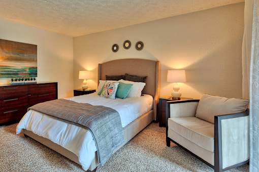 A bedroom with a large bed and a smaller bed with a white chair beside it.