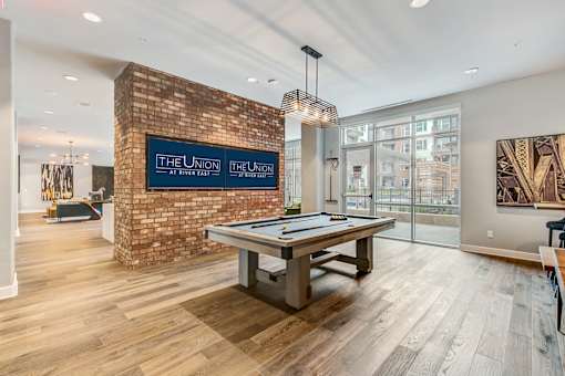 A room with a pool table and a brick wall with a sign that says The Union.