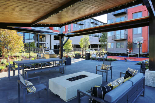 an outdoor lounge area with a firepit and a basketball court