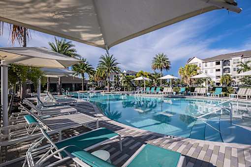A large outdoor swimming pool with sun loungers and umbrellas.