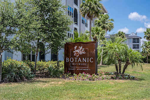 A sign for Botanic Waterside Apartments is in front of a building.