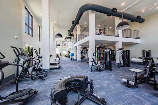 A spacious gym with a variety of equipment including treadmills, weights, and a rowing machine.