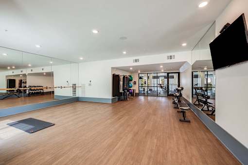 A gym with wooden floors and mirrors on the wall.