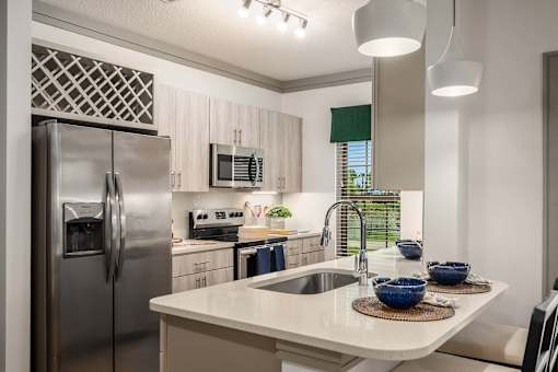 A modern kitchen with a stainless steel refrigerator and a white countertop.