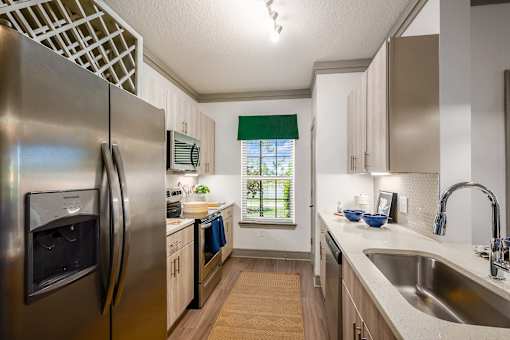 A kitchen with a stainless steel refrigerator and wooden cabinets.