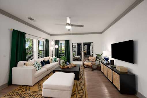 A living room with a white couch and a flat screen TV mounted on the wall.