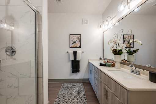 A bathroom with a marble shower and a sink with a mirror above it.