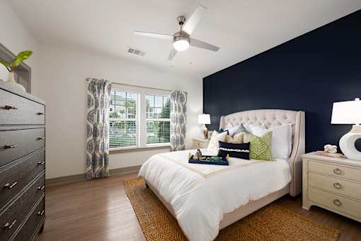 A bedroom with a bed, dresser, and window.