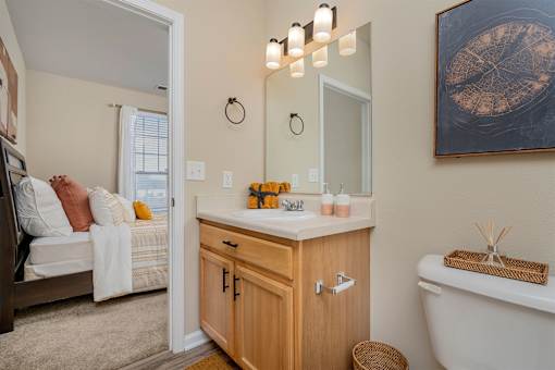 A bathroom with a white tub, wooden vanity, and a painting on the wall.