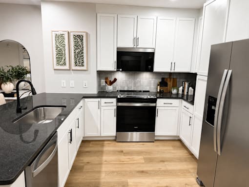 A modern kitchen with white cabinets and a stainless steel refrigerator.