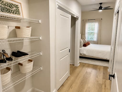 A white closet with shelves and baskets holding shoes.
