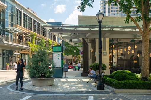 A street view of a shopping area with a woman walking on the left side.