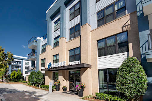 A modern building with a balcony and a small garden in front.