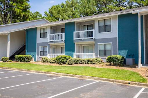 A blue and white apartment building with a parking lot in front.