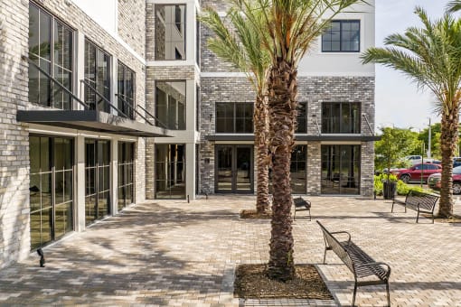 a courtyard with benches and palm trees in front of a building  at Leena Plantation, Florida, 33322