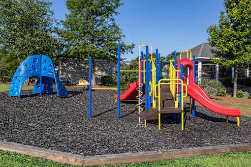A playground with a blue and yellow slide and a red slide.