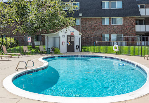 A small white building is located next to a blue swimming pool.