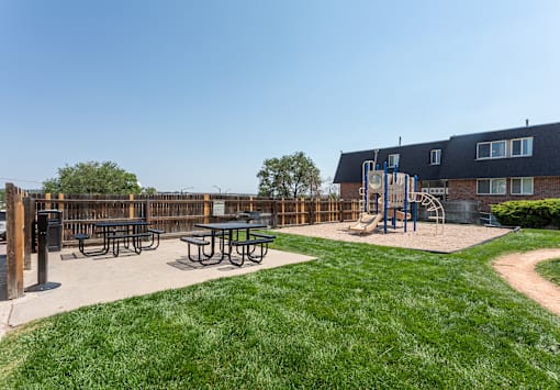 A playground with a slide, swings, and picnic tables.