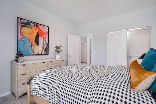 A bedroom with a bed, dresser, and a painting on the wall.