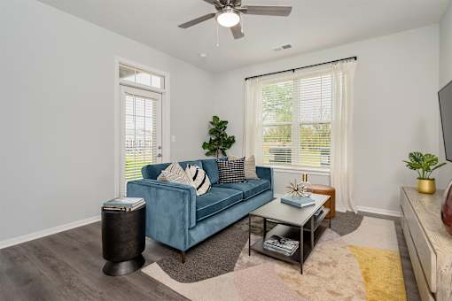 A living room with a blue couch and a ceiling fan.