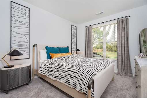 A bedroom with a bed, nightstand, and window.